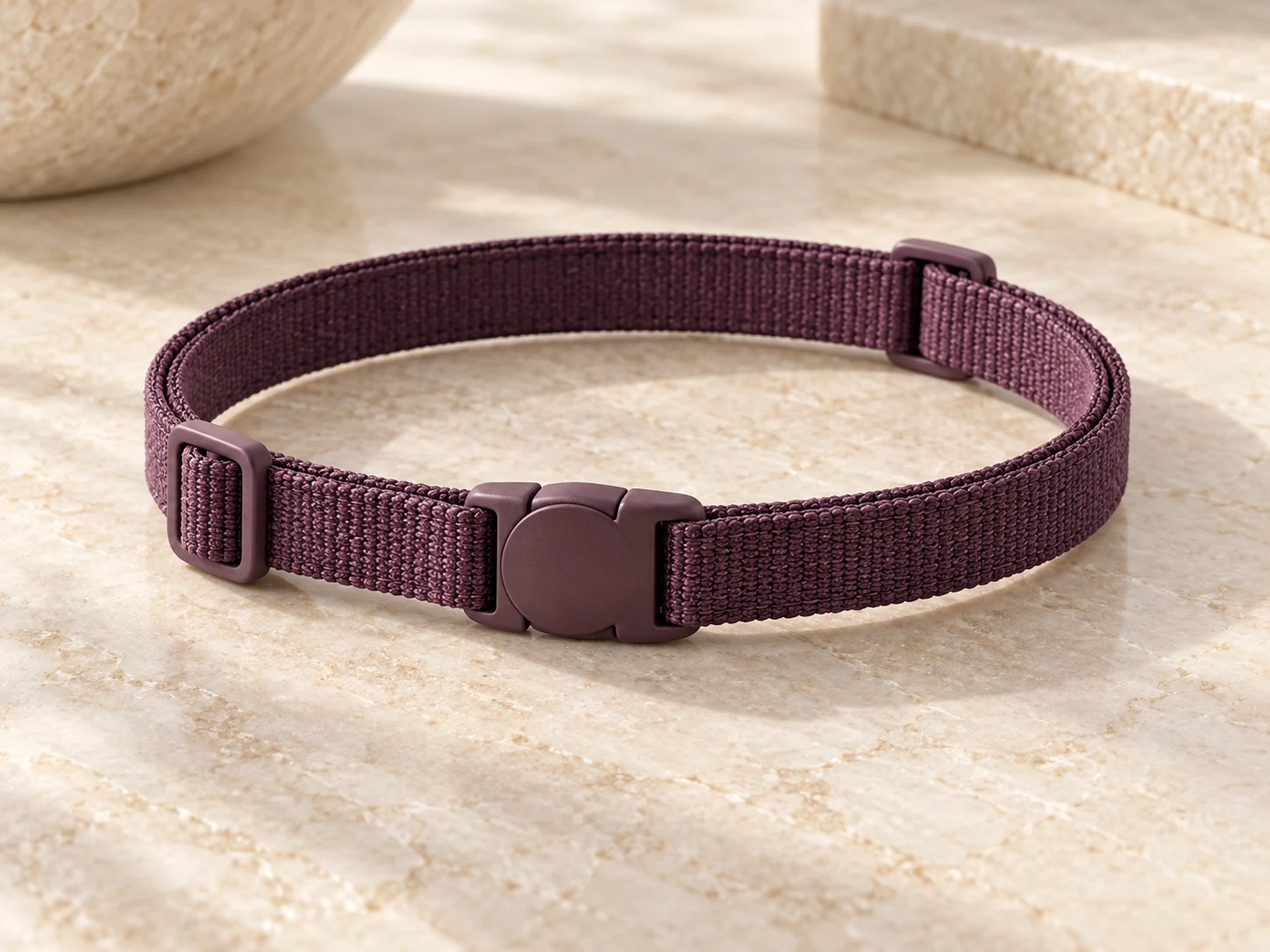 Illustrative plum fabric neck band on a pale stone surface